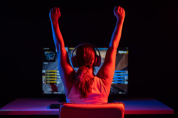 Caucasian woman rejoices at winning a computer game in neon light in the dark.