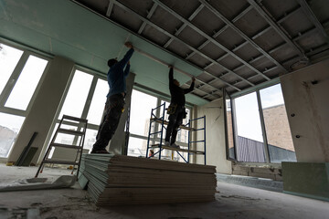 Drywall Installers. Men holding a gypsum board figured cut