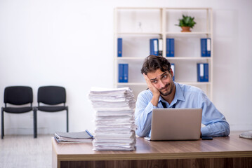 Young male employee and too much work in the office
