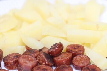 cooked potato with sausage. sliced ​​sausage with potato. meal with selective focus. sausage and potato.