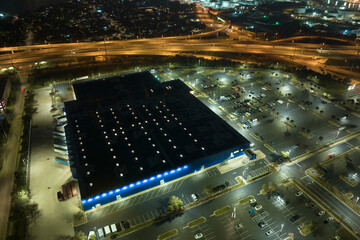 Aerial view of large parking lot at nighttime with many parked cars. Dark carpark at supercenter shopping mall with lines and markings for vehicle places and directions © bilanol