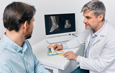 Orthopedic doctor consulting adult man with pes planus, explaining treatment methods using...