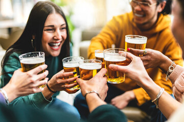group of people cheering and drinking beer at bar pub table -Happy young friends enjoying happy...