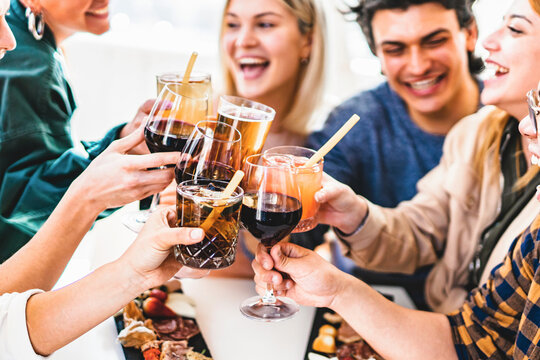 Group of friends toasting fancy cocktails together sitting at bar restaurant table-Happy young people celebrating party enjoying happy hour with wine and beer-Food and beverage lifestyle concept