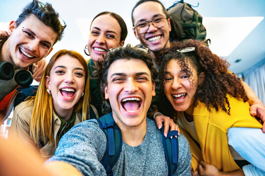 Happy multiracial friends travelers taking selfie shot at hostel reception- Young group of people having fun together looking at camera-Life Style concept with trendy students 