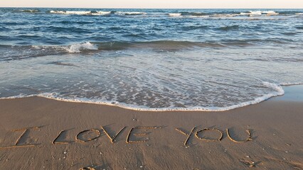 Fototapeta na wymiar I love you scritto sulla spiaggia in riva al mare