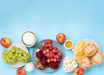 Jewish Shavuot Holiday Card. Dairy Products, Grapes, Cheese, Bread, Milk on Blue Background.
