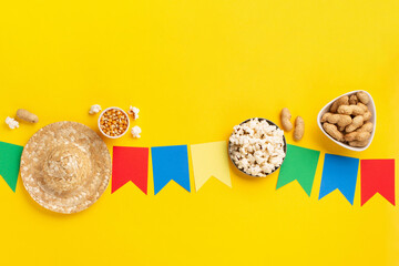 Brazilian straw hat, popcorn, peanuts and colorful flags on yellow background for Brazilian Festa Junina Summer Festival