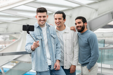 Group Of Three Male Friends Travelling Making Selfie In Airport