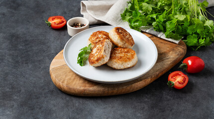 Fried meatballs on a plate on a dark background with fresh tomatoes and herbs. Homemade healthy and delicious food.