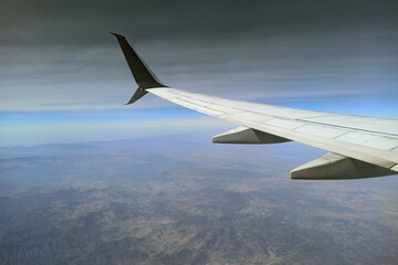 View through airplane window of commercial jet plane wing flying high in the sky. Air travelling concept