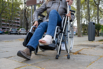 Obraz premium Injured woman in a wheelchair and carrying crutches.