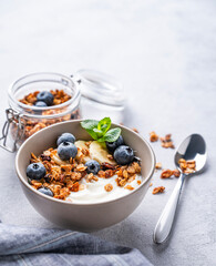 Muesli with vegetarian yogurt, banana and blueberries in a bowl on a light background close up. Healthy and dietary homemade granola for breakfast.