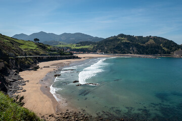 A praia em Deba na costa Basca em Espanha num bonito dia com o céu azul e com algumas casas e...
