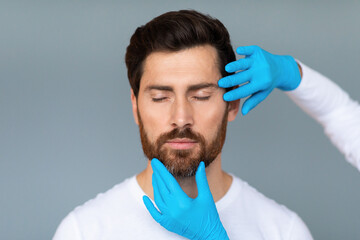 Portrait of bearded middle aged man getting prepared for plastic surgery procedures, doctor...