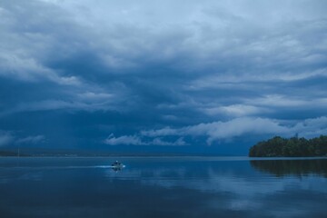 Evening view of a blue sea with people on a small boat with mountains in the background