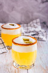 Spicy cocktail with margarita, egg white foam, tagine and jalapeno peppers in glasses vertical view