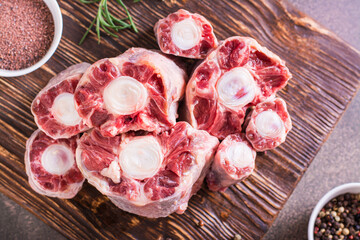 Close up of raw sliced oxtail, spices and rosemary on a wooden board top view