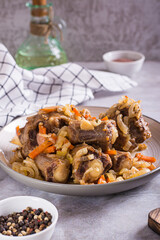 Stewed oxtail with carrots and onions on a plate on the table vertical view