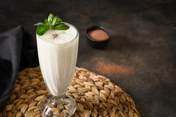 Indian Salty lassi with mint leaves and kala namak on black background. Traditional freshness lassi made of yogurt, water, spices and ice for hot climate. Close up. Copy space.