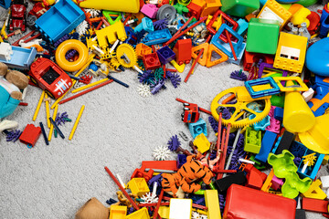 An abundance of toys in the children's room, a lot of plastic multi-colored parts from designers, spare parts for toys, figurines and cubes.