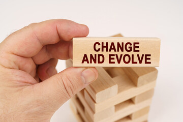 A man holds in his hands a wooden block with the inscription - Change and evolve