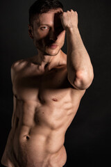 Adult attractive man with a beautiful body posing in the studio. Black background.	