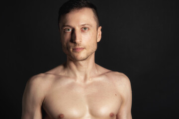Fototapeta premium Adult attractive man with a beautiful body posing in the studio. Black background. 