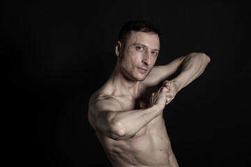 Obraz na płótnie Canvas Adult attractive man with a beautiful body posing in the studio. Black background. 