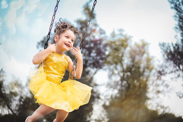 beautiful junior little girl playing in the park in yellow dress laughing with bubbles, screaming...