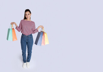 Happy pretty hispanic woman holding colorful shopping bags, copy space