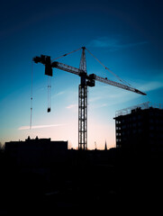 Construction crane silhouette after sunset with cityscape at background, vertical photo. High quality generative ai