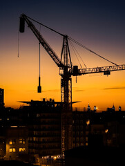 Construction crane silhouette at sunset with cityscape at background, vertical photo. High quality generative ai