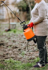 Woman gardener holds in her hands a sprayer with poison from harmful insects. Photography, nature, gardening.