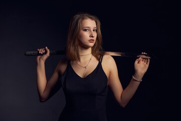 Young female with katana on black background