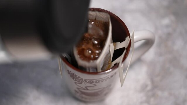 Drip coffee bag, brews coffee in a glass mug. Close up