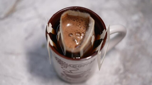 Drip coffee bag, brews coffee in a glass mug. Close up