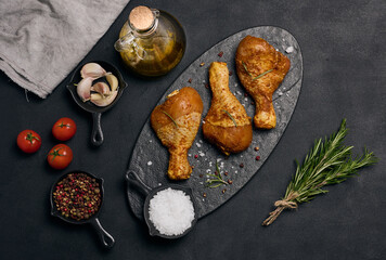 Raw chicken legs in spices on a black board, top view. Cooking with spices