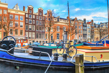 Cityscape on a sunny winter day - view of the houseboats on the water canal in the historic center of Amsterdam, the Netherlands