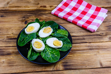 Spinach leaves and halved boiled eggs on a black plate