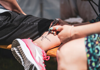 Uzdolniony artysta starannie wykonujący tatuaż henną z precyzją i kreatywnością. © LPPhotography