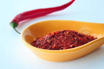 red chili flakes or powder in a spoon on white 