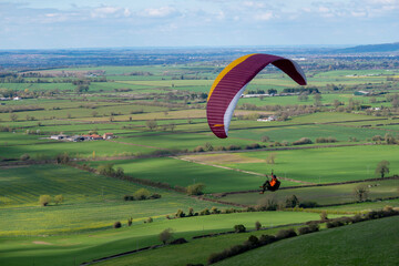 A single paraglider flying over Westbury escarpment in Wiltshire