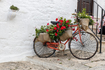 Fototapeta na wymiar Beautiful view of a decorative old bicycle with flowers and a garland in Ostuni.