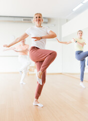 Caucasian woman learning aerobic dance during group training in studio.