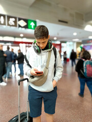 Young man standing in a station looking at his cell phone