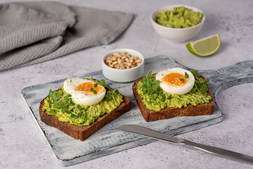 Food photography of sandwich with rye bread, egg, avocado, cress salad, pine nuts, lime, toast,...