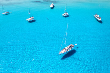 Aerial view of beautiful luxury yacht and sailboats in blue sea at sunset in summer. Sardinia...