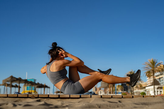 a beautiful girl goes in for sports does functional training exercises on the press on the seashore at dawn and takes pictures of herself on the phone. stream. online training