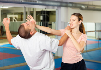 Fototapeta na wymiar Woman and man practicing self defense techniques in gym